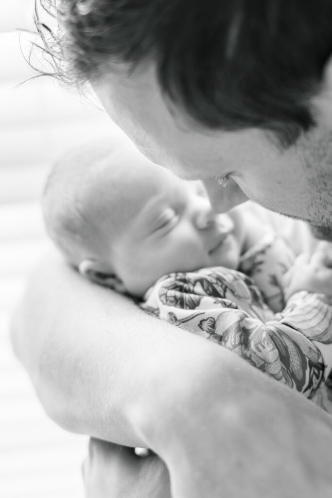 A father is rubs his nose against his newborn baby's nose in this black and white photo beautifully captured by an Austin newborn photographer.