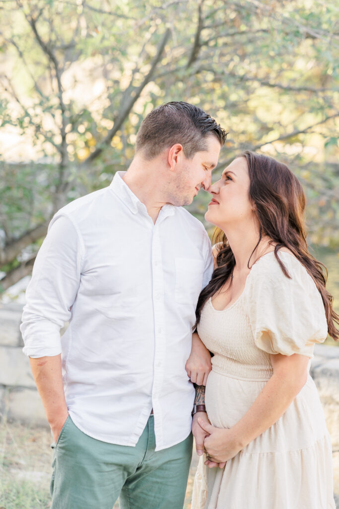 A man and a woman stand facing each other with their noses touching. The woman has one arm wrapped around the man's right arm while holding his hand with her other arm in this sweet moment captured by an Austin Family Photographer.