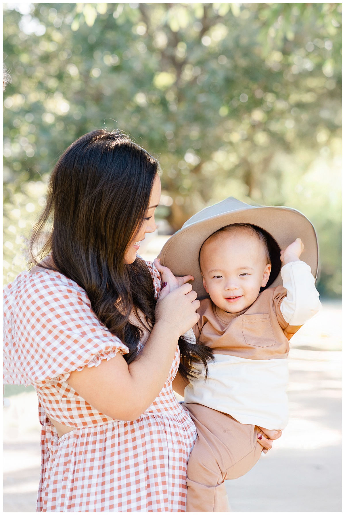 Best Photo Locations in Austin | A mother holds her little boy in her arms. The little boy is wearing his mother's hat. 