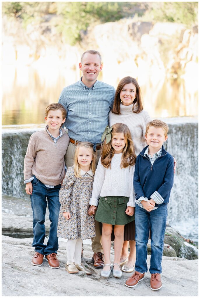 family of six with two boys and two girls standing in front of waterfall in this family photo taken at blue hole park in georgetown, tx by a Georgetown Texas Photographer.