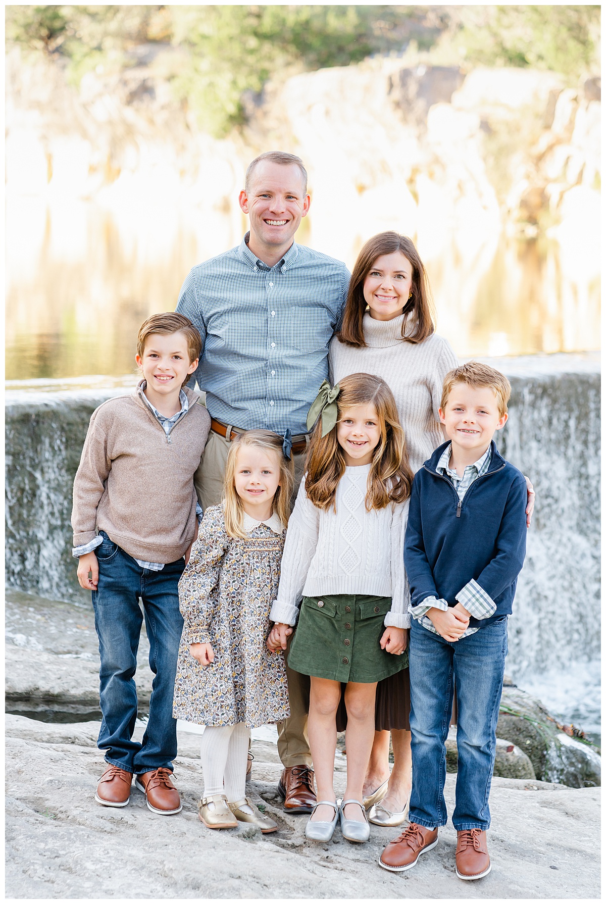 family of six with two boys and two girls standing in front of waterfall in this family photo taken at blue hole park in georgetown, tx by a Georgetown Texas Photographer.