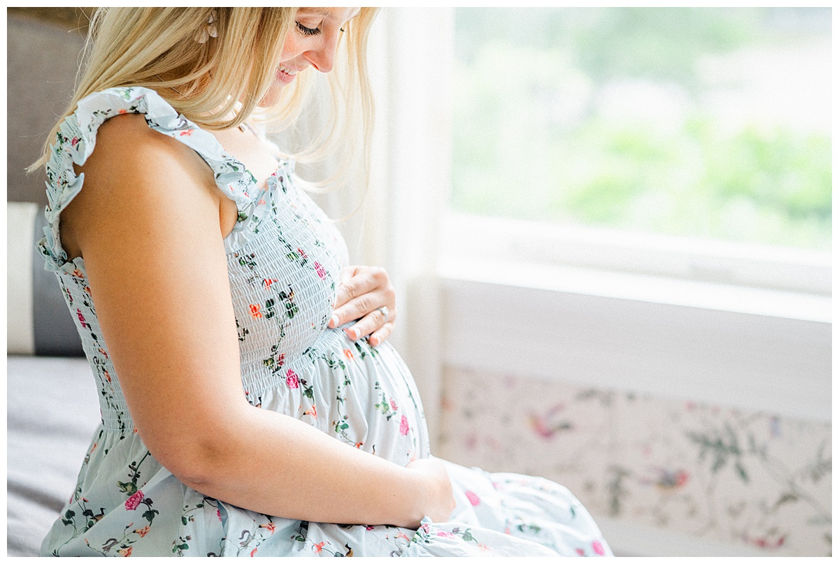A pregnant woman sits on the edge of a daybed at the Woodbine Mansion. The photo, taken by an Austin Maternity Photographer, focuses on her pregnant belly.