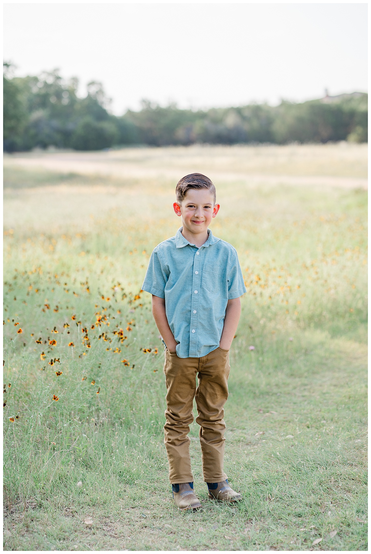 A young boy stands in front of a field during his wildflower family photos. He poses and smiles at the camera of a Cedar Park Photographer.