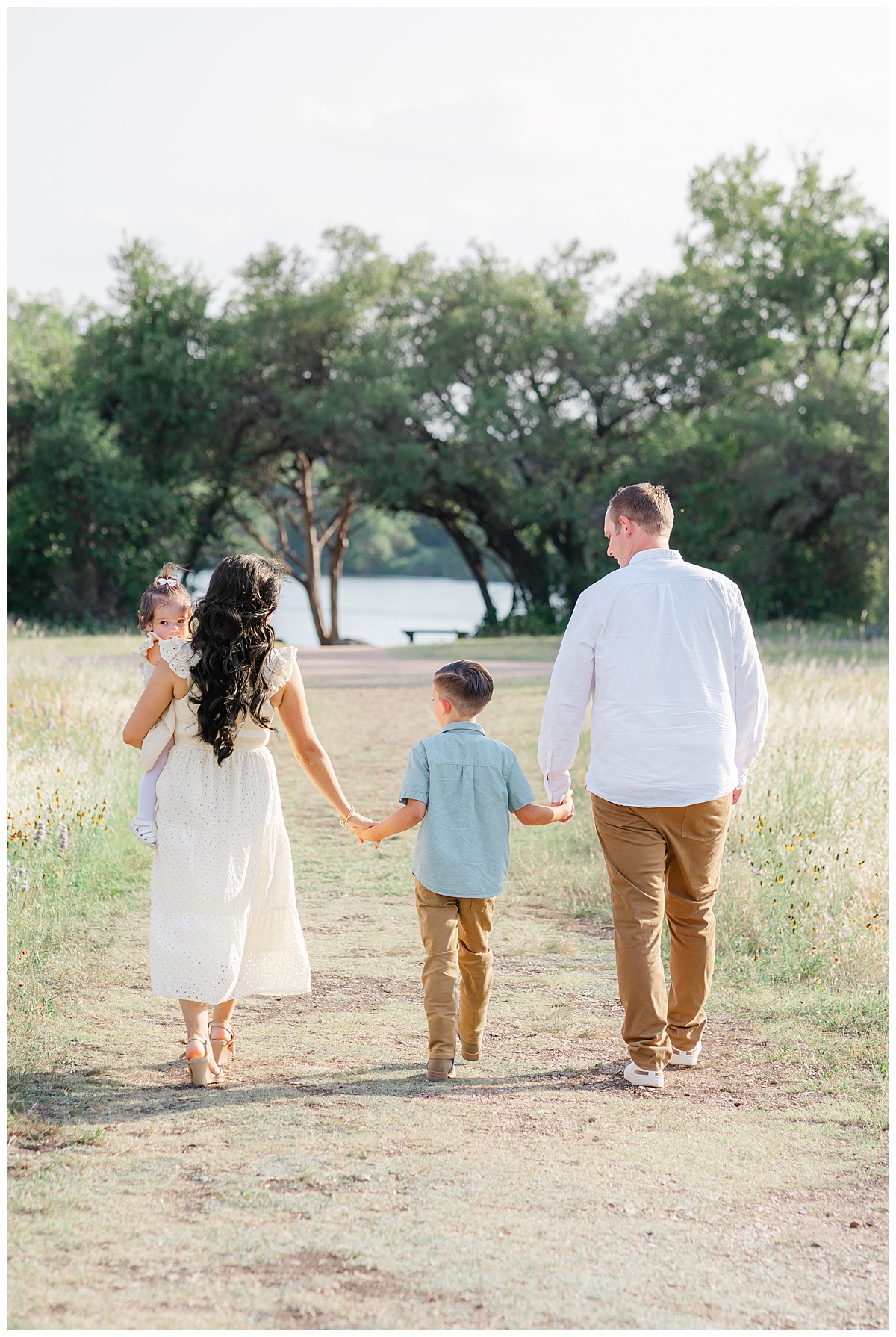 A family of four walks away on a sandy path leading to a lake at Brushy Creek in Cedar Park, TX.