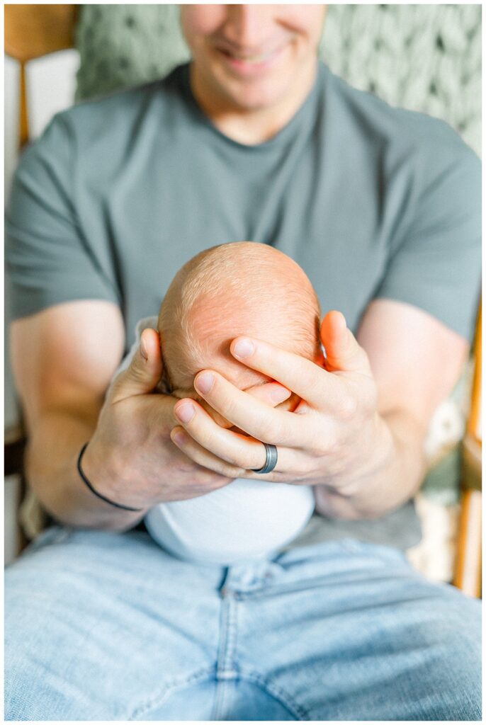 A detailed shot of a newborn's head held by his father and captured by a Georgetown, TX in-home newborn photographer.