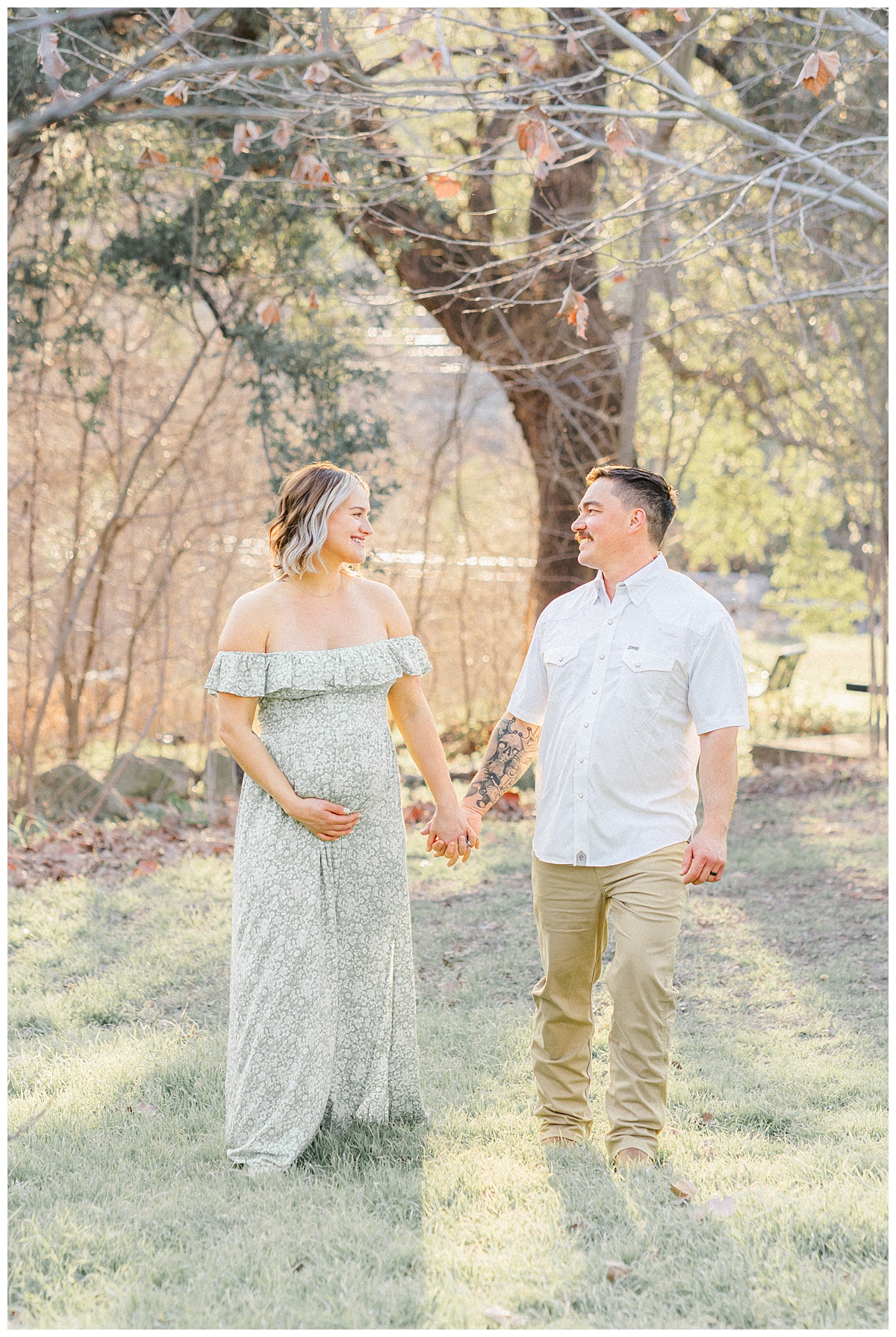 A couple walks while they hold hands at Bull Creek District Park. They look at each other and smile during their maternity photoshoot in Austin, TX.