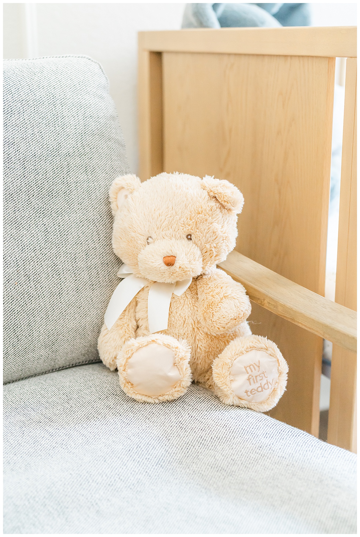 a beige teddy bear sits on a grey rocky chair in a baby nursery in Leander, TX.