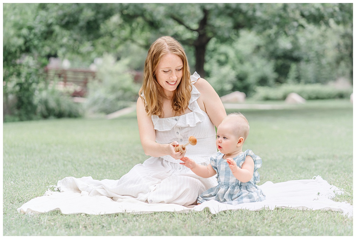 Austin Baby Photography | a mother and her 6-month baby girl sit on a blanket and play with a rattle at Katherine Fleischer Park.