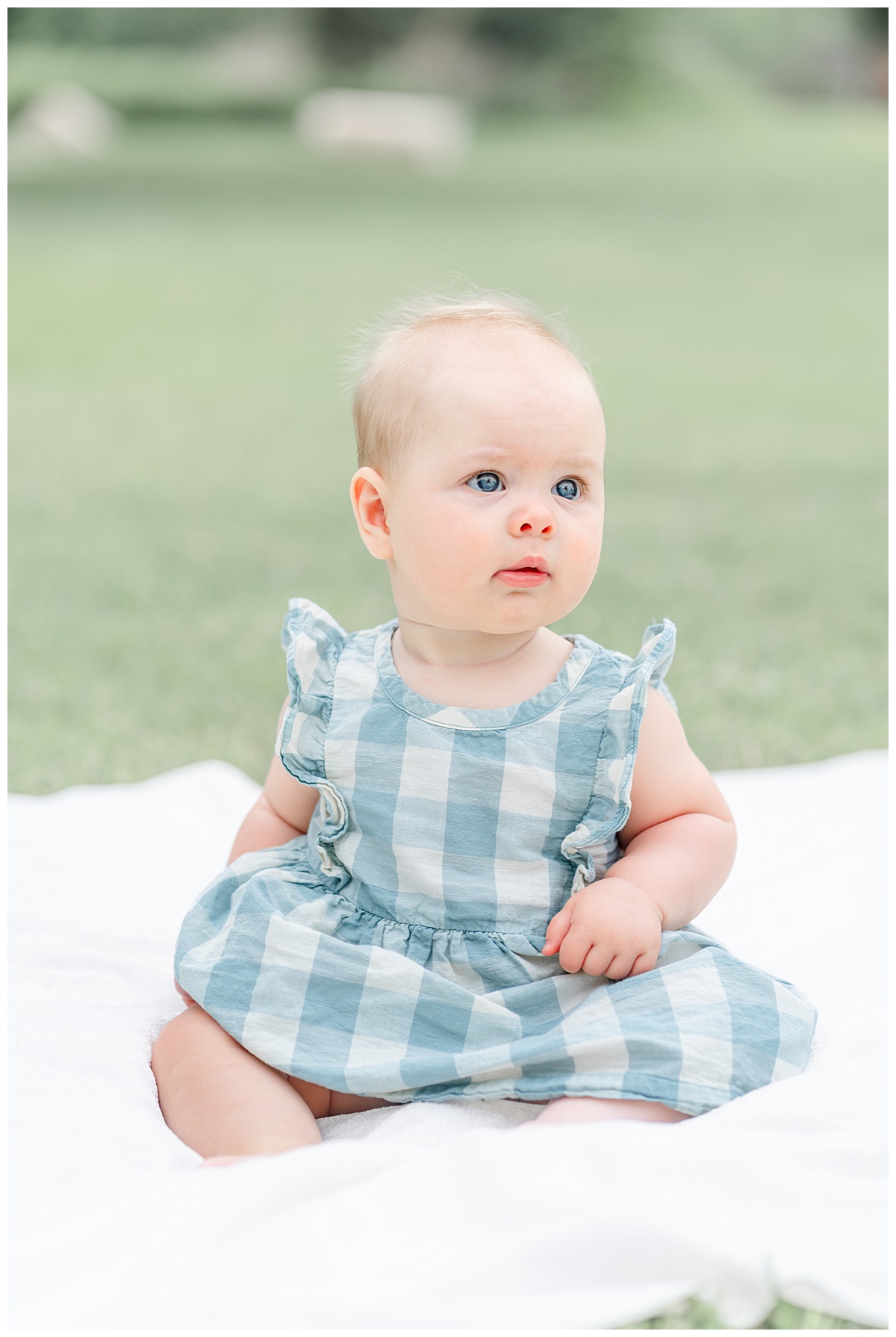 Austin Baby Photography | Baby girl sitting on a blanket wearing a blue gingham dress for her 6-month photos.