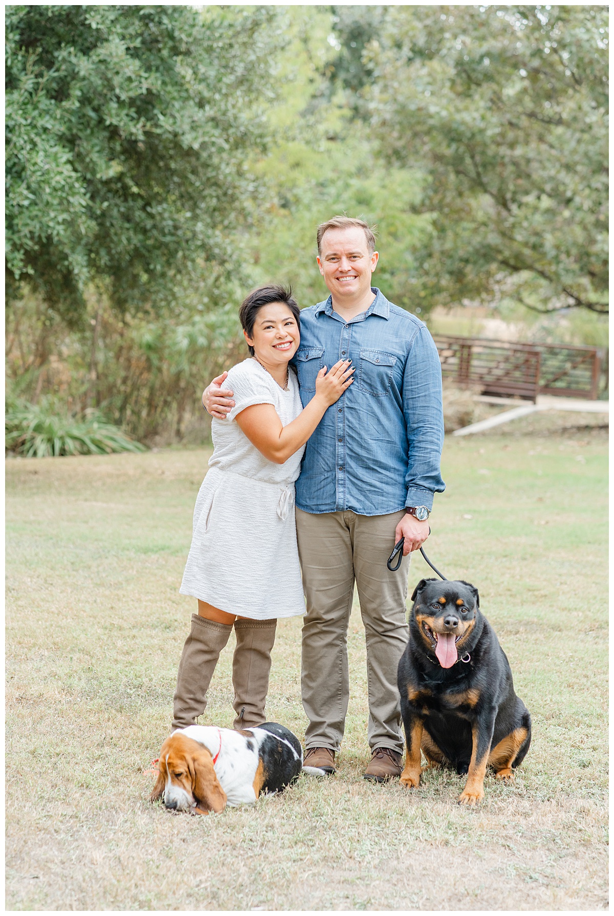 a couple stands together with a small and a big dog during their photo session at Katherine Fleischer Park.