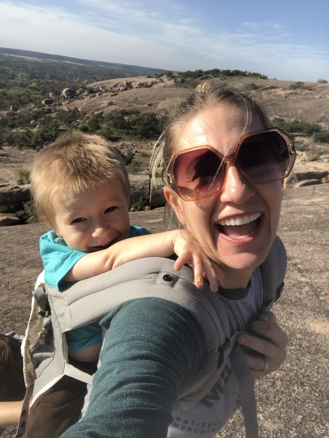 the owner of the family blog Austin Fun For Kids and her toddler are hiking. She carries her toddler on her back.