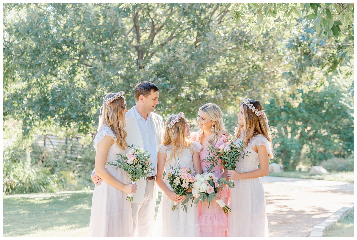 A family with three teenage girls stands under a tree at Katherine Fleischer Park in Austin for their anniversary family photos.