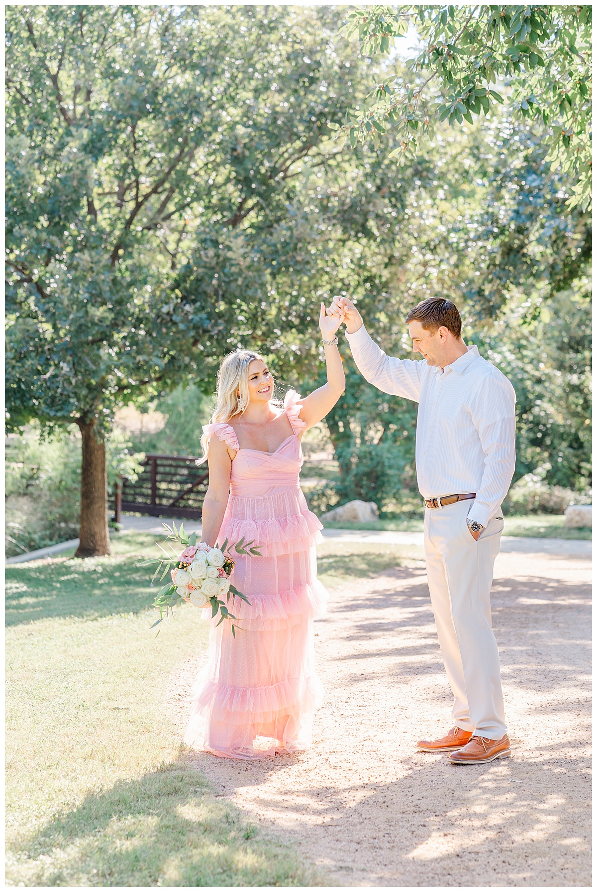A couple with a woman dressed in a long pink dress dance on a path at Katherine Fleischer Park in Austin. 