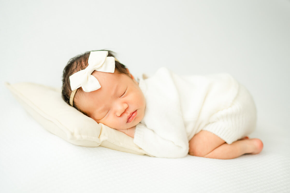 infant laying on white bean bag during Austin newborn session.