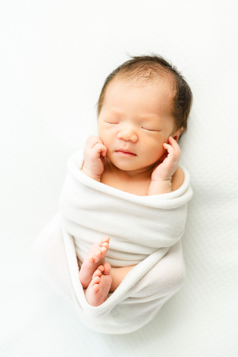 infant girl wrapped in white blanket for her Austin Newborn Photography session.