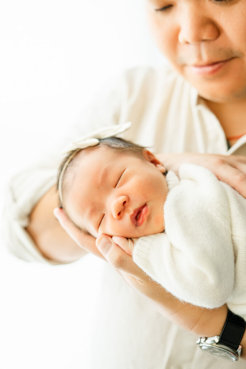 infant rests on father's hand during newborn session in Austin.