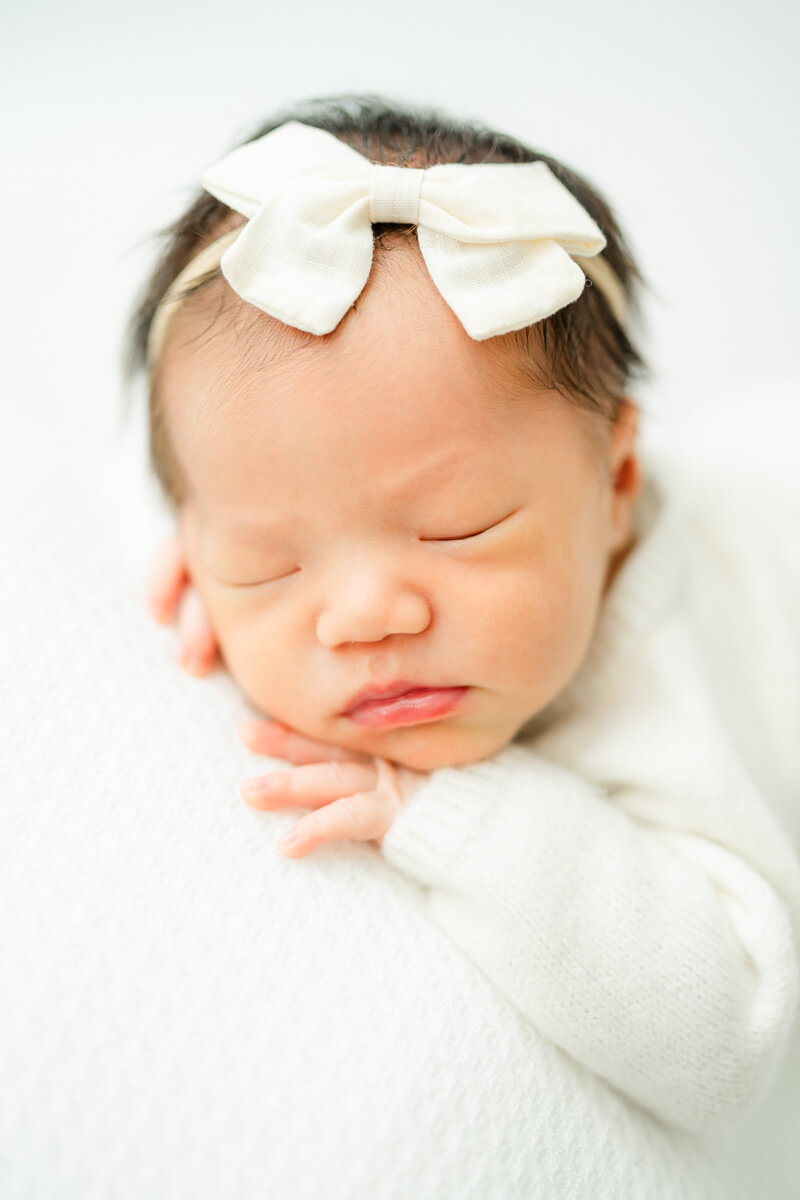 posed portrait of newborn girl in white outfit.