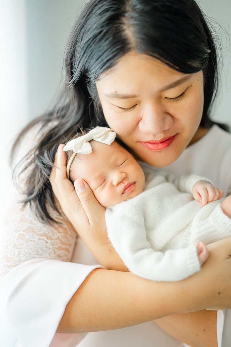 mother holds infant daughter up to her cheek for newborn portraits in Austin, TX.