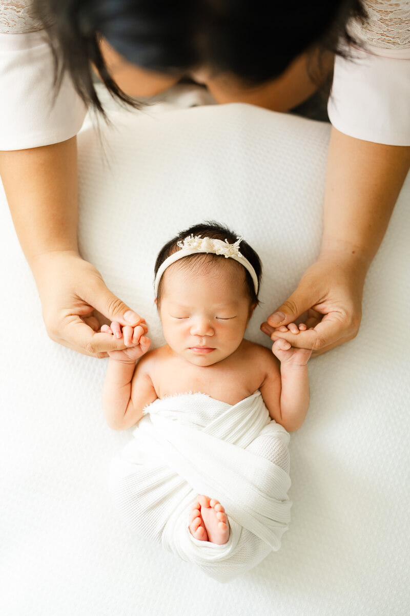 mother holds her newborn's hands during their Austin newborn photo session.