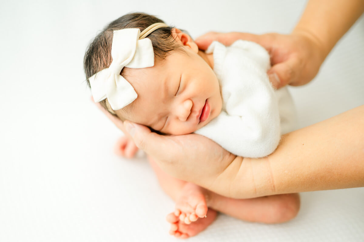 posed newborn portrait with father holding baby in hands.